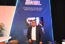 Exel del Norte transforma el ecosistema de canales mediante la inteligencia artificial y disponibilidad de inventario Fotografía en plano medio de Amador Rangel, Encargado de la gerencia de Dell Technologies cómputo en Exel del Norte, vistiendo un saco oscuro sobre una camisa blanca, posando sonriente frente a un muro azul con iluminación neón y la frase "EXEL, LO MEJOR EN TECNOLOGÍA PARA HACERTE CRECER".