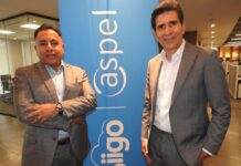 El canal encuentra en Siigo Aspel a su mejor aliado para capitalizar la reforma laboral Fotografía en plano medio de Carlos Antonio Ibáñez y Eduardo Pérez posando juntos de pie sonrientes a los lados del pendón publicitario azul de Siigo Aspel.
