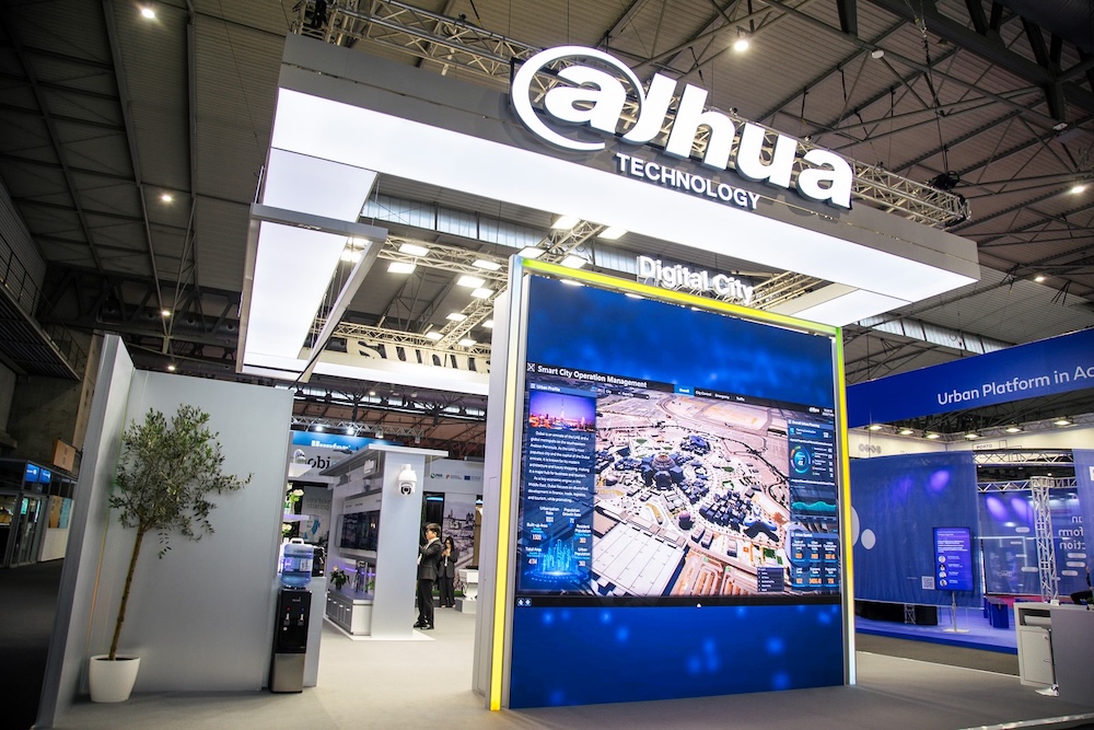 Fotografía en perspectiva del estand de exhibición interactivo de Dahua Technology en una feria industrial, destacando la estructura iluminada con el logotipo de la marca y pantallas gigantes con soluciones para ciudades inteligentes.