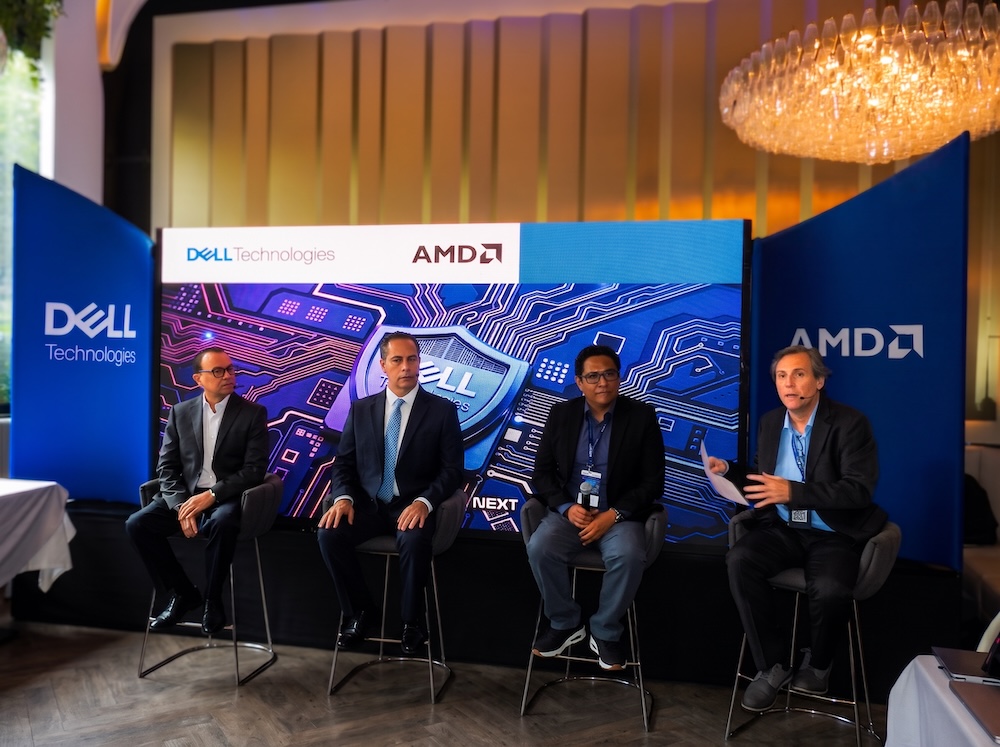 Dell Technologies y AMD encabezan panel sobre resiliencia, hardware y seguridad agéntica con IA Fotografía en plano general de cuatro panelistas sentados en un escenario frente a una gran pantalla azul de Dell Technologies y AMD, participando en un panel ante mesas de invitados.