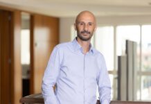 Ricoh: El integrador tecnológico y la próxima ventaja competitiva de las empresas Fotografía de retrato en plano medio de Diego Imperio, Presidente y CEO de Ricoh LATAM, vistiendo una camisa de vestir azul claro y posando sonriente y apoyado en un barandal de madera dentro de un entorno corporativo iluminado.