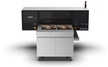 Epson y Alpha Beta impulsan la impresión profesional en Expo Photo Master Class 2026 Fotografía en render de producto con vista frontal de la impresora UV de cama plana Epson SureColor V4000 de color gris y negro sobre un fondo blanco aislado, mostrando impresiones de retratos fotográficos en su cama de trabajo.