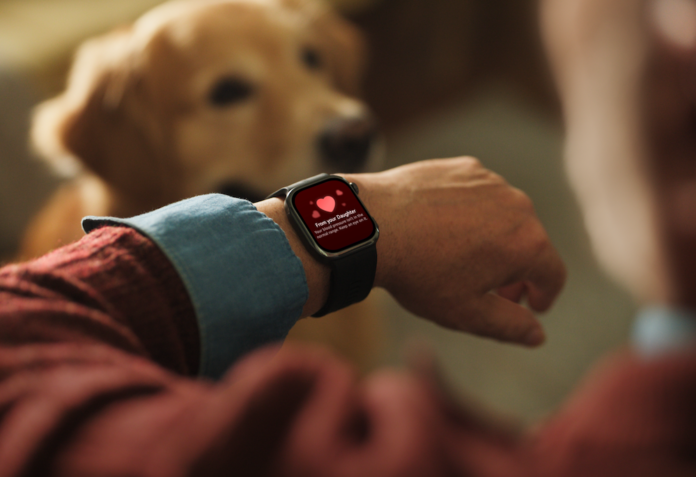 Fotografía en primer plano de la muñeca de una persona usando el reloj inteligente HUAWEI WATCH D3 negro, mostrando en pantalla una alerta familiar con un corazón rojo y el mensaje 