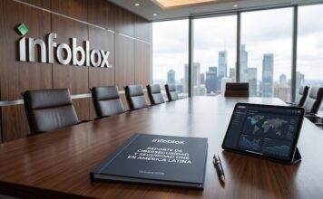 Infoblox impulsa la ciberseguridad preventiva frente a la automatización del cibercrimen Fotografía de una sala de juntas corporativa de Infoblox con un ventanal que muestra un horizonte de rascacielos, sobre cuya mesa de madera se observa una tableta con un mapa de ciberamenazas mundiales y el documento impreso del Reporte de Ciberseguridad y Seguridad DNS en América Latina.