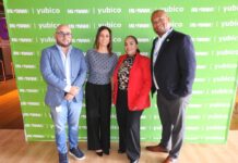 Ingram Micro y Yubico cierran la puerta a los ataques impulsados por inteligencia artificial en México Fotografía en plano entero de los cuatro directivos (Óscar López, Carmen Morales, Viridiana Hernández y Clifton Slater) posando juntos y sonrientes frente a un muro de prensa verde con los logotipos de Ingram Micro y Yubico.