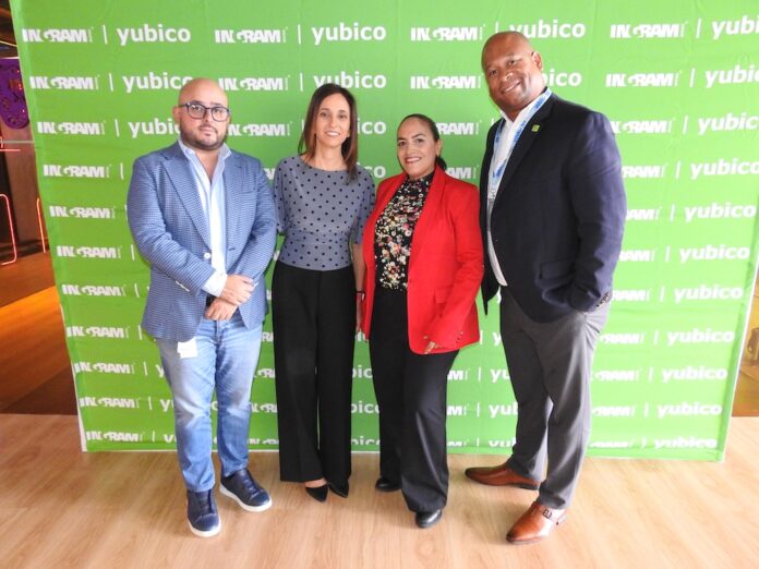 Fotografía en plano entero de los cuatro directivos (Óscar López, Carmen Morales, Viridiana Hernández y Clifton Slater) posando juntos y sonrientes frente a un muro de prensa verde con los logotipos de Ingram Micro y Yubico.