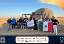 Grupo CVA fortalece su ecosistema tecnológico desde Marruecos e impulsa una nueva etapa de innovación Fotografía grupal en plano entero de ejecutivos y fabricantes posando sonrientes frente a un globo aerostático posado en el suelo del desierto, sosteniendo la bandera de México y la bandera corporativa de CVA.