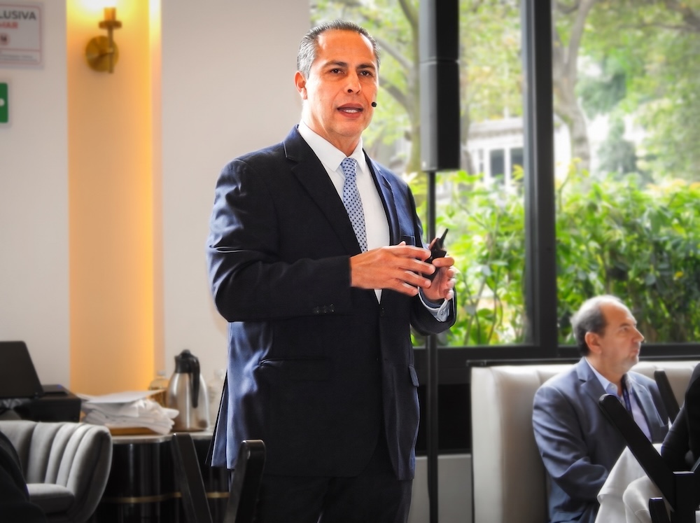 Fotografía de plano medio de Juan José Cisneros, Presidente de CISO Club, de pie vistiendo traje oscuro con corbata azul y gesticulando mientras imparte una conferencia magistral.