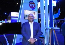 CT Internacional y su visión de liderazgo para transformar el canal TI Fotografía en plano medio de Juan Pablo Rojo, Director Adjunto de Marcas en CT Internacional, luciendo un saco azul marino sobre camisa blanca, posando sonriente con las manos entrecruzadas frente al estand con iluminación azul y pantalla interactiva del mayorista.