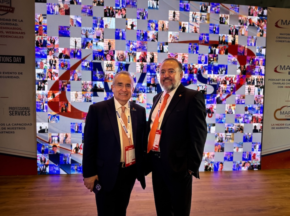 Liderazgo directivo de MAPS Disruptivo reafirma su compromiso con la evolución del canal Fotografía de retrato en plano medio de Luis Badó, Director de Operaciones de MAPS, y Martín Mexía, CEO de MAPS, vistiendo trajes ejecutivos oscuros y posando sonrientes frente a un mural digital con mosaico de fotografías del evento.