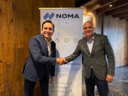 Tasmicro incorpora Noma Security a su portafolio para fortalecer la seguridad y gobernanza de agentes de IA en México y Latinoamérica Fotografía de plano medio de Víctor Anda, Director Regional de Ventas para Latinoamérica de Noma Security, estrechando la mano de Sergio Hernández, Socio Director de Tasmicro, sonriendo frente a un banner publicitario de Noma Security en una oficina con acabados de madera.