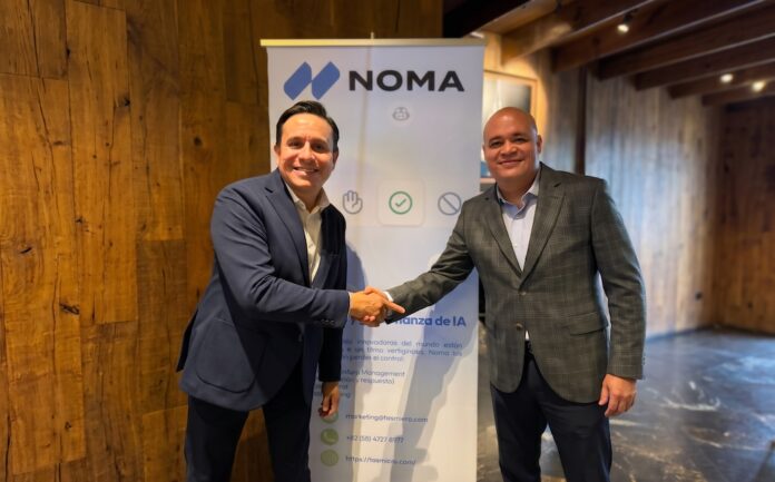 Noma Security y Tasmicro formalizan alianza estratégica para la gobernanza y seguridad de agentes de IA en Latinoamérica Fotografía de plano medio de Víctor Anda, Director Regional de Ventas para Latinoamérica de Noma Security, estrechando la mano de Sergio Hernández, Socio Director de Tasmicro, sonriendo frente a un banner publicitario de Noma Security en una oficina con acabados de madera.