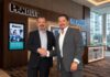 Impulso estratégico al canal de distribución tras la alianza entre Panduit e Ingram Micro Fotografía en plano medio de Carlos Arochi, Director de Panduit Latam, y Gerardo Romero, Director de Ingram Micro México, estrechando la mano sonrientes frente a los logotipos iluminados de Panduit e Ingram Micro en un entorno corporativo.