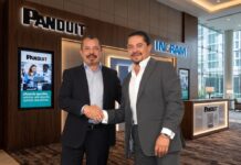 Impulso estratégico al canal de distribución tras la alianza entre Panduit e Ingram Micro Fotografía en plano medio de Carlos Arochi, Director de Panduit Latam, y Gerardo Romero, Director de Ingram Micro México, estrechando la mano sonrientes frente a los logotipos iluminados de Panduit e Ingram Micro en un entorno corporativo.