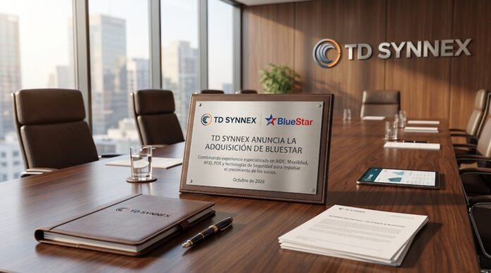 Fotografía de una placa conmemorativa metálica sobre una mesa de madera en una sala de juntas corporativa con vista panorámica a la ciudad y el logotipo de TD SYNNEX al fondo, donde se lee el anuncio de adquisición de BlueStar fechado en octubre de 2026.