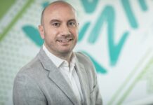 Veeam: La incómoda lección de octubre; sin resiliencia, la seguridad cibernética no es suficiente Fotografía de retrato corporativo en primer plano de Tomas Dacoba, sonriendo en saco gris claro sobre un fondo con patrones gráficos en tonos verde y blanco.