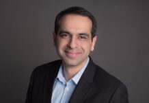 El despertar de los datos: Dell Technologies marca la ruta hacia una inteligencia artificial confiable Fotografía de retrato en plano medio de Varun Chhabra, Vicepresidente Senior de Marketing de Producto en el Grupo de Soluciones de Infraestructura de Dell Technologies, vistiendo un saco negro sobre una camisa azul claro, posando sonriente frente a un fondo neutro gris.